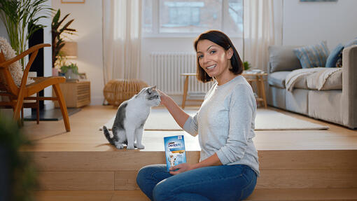 Lady sat with her cat holding Dentalife cat sticks